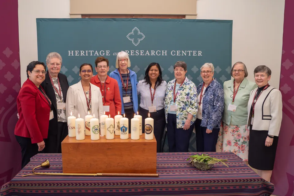 Sisters and staff gathered behind a table of lit congregation candles at HARC