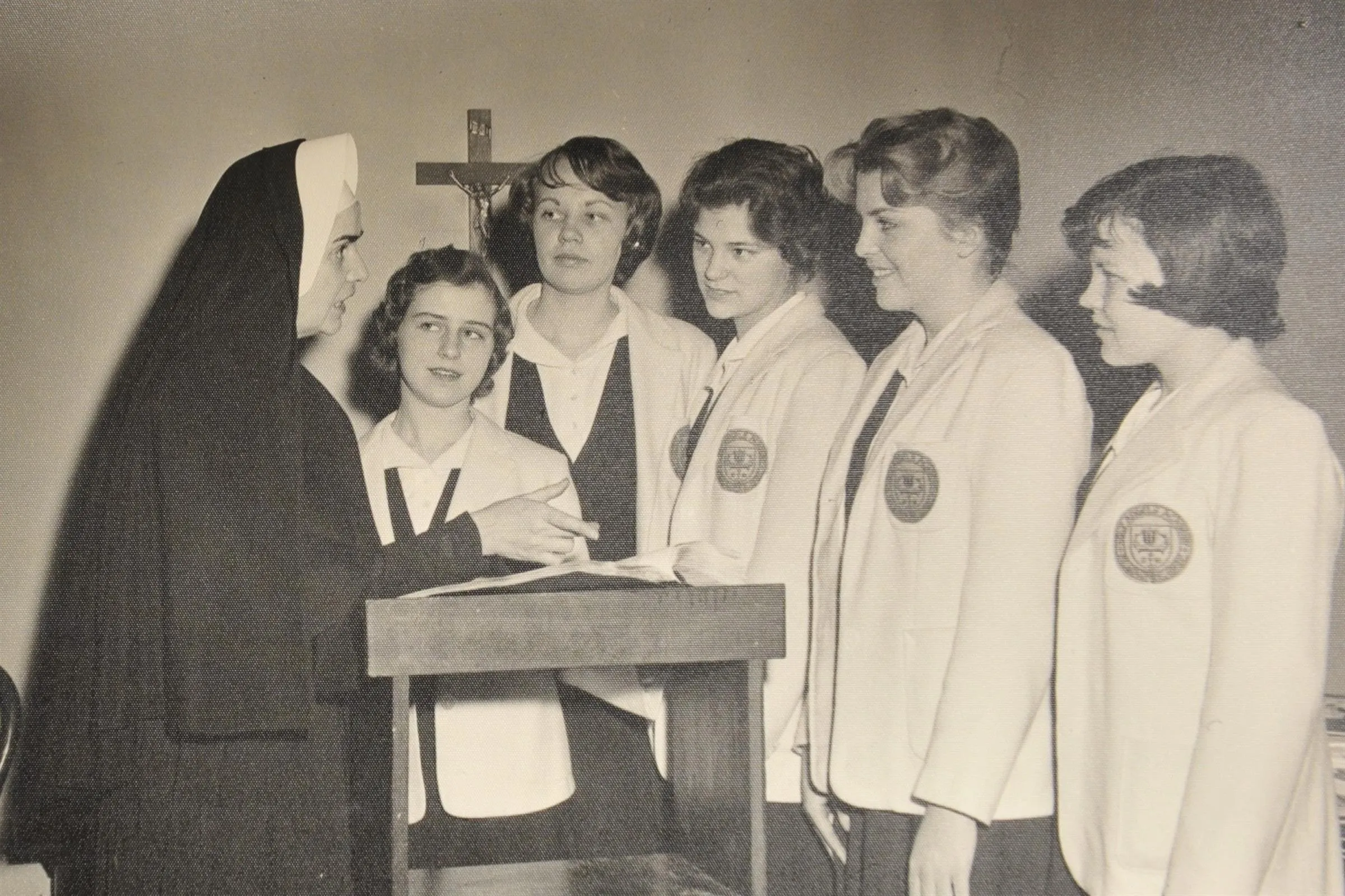 Archival photograph of sisters and students gathered at a lectern