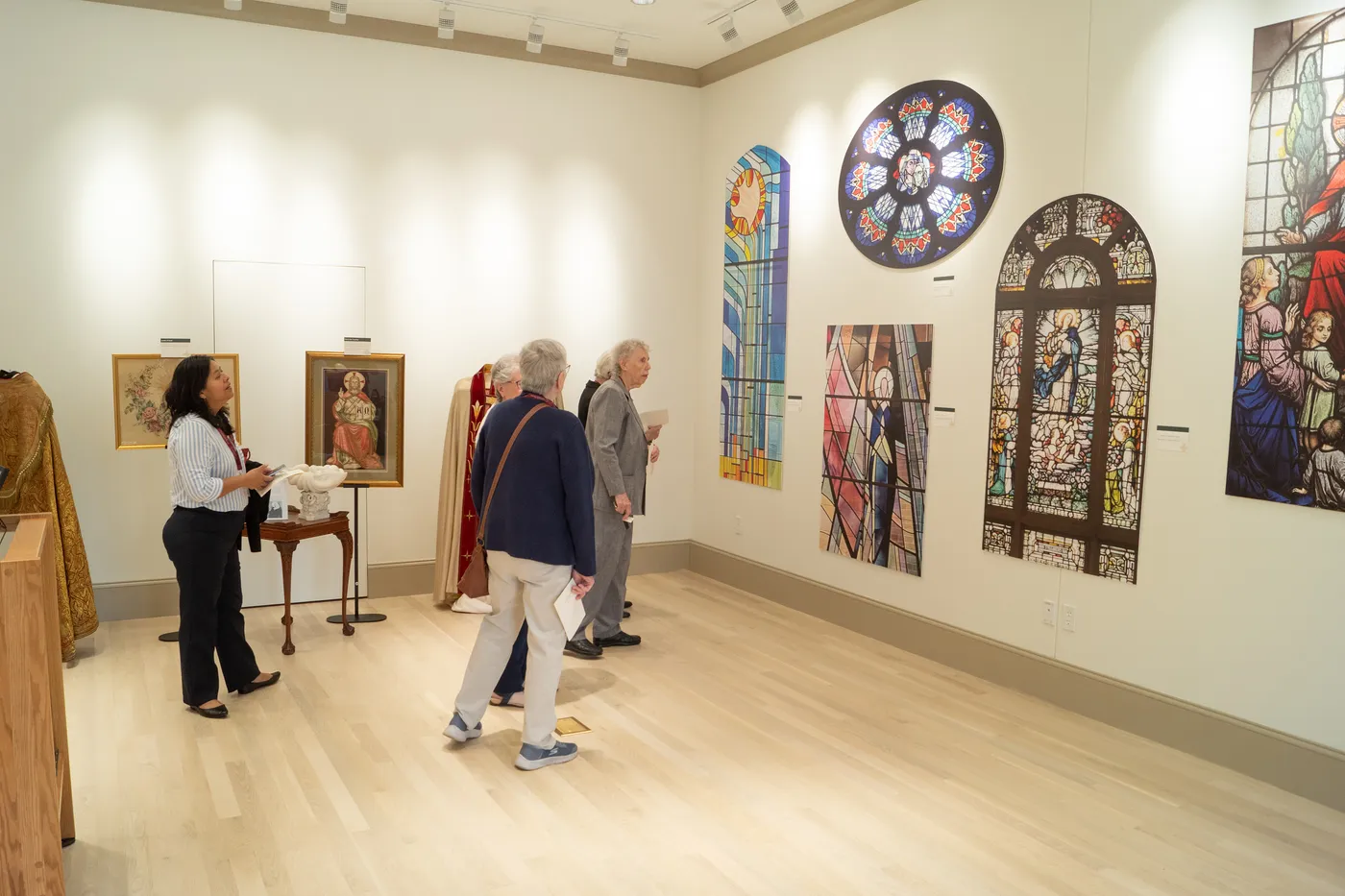 Visitors viewing framed artwork and stained glass panels in the HARC gallery