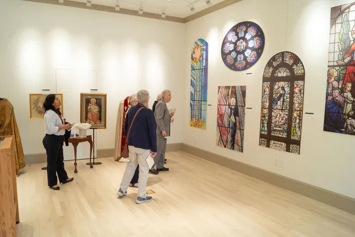 Visitors viewing framed artwork and stained glass panels in the HARC gallery