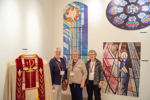 Sisters and staff standing beside stained glass and vestment displays at HARC